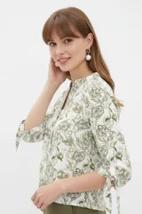 Blusa estampada de viscosa con diseño abstracto en tonos beige, negro y marrón, escote en V con cuello mao y mangas tres cuartos con detalles de lazos en los puños.