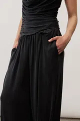 Pantalón holgado negro tipo bombacho, con cintura elástica y puños fruncidos en los tobillos.