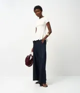 Blusa de corte peplum confeccionada en tejido Punto Roma, con escote redondo, mangas cortas y recortes estructurados que definen la silueta.