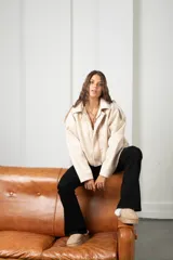 Campera de gamuza color beige, con diseño tipo globo, cuello camisero, cierre frontal y mangas amplias.