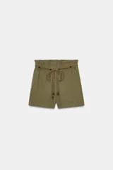 Bermuda color verde militar de tiro alto con cintura elástica y cinturón marrón con abalorios. Presenta bolsillos laterales ocultos y cierre frontal con cremallera y gancho metálico.