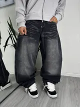 Jeans baggy de corte ancho, color negro con efecto gastado y lavado ácido, tiro medio y costuras contrastantes.
