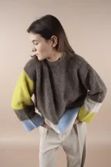 Sweater de lana multicolor con cuello redondo y mangas largas. Diseño con bloques de color en marrón, amarillo, celeste y blanco.