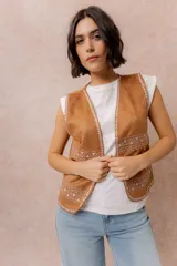 Chaleco corto de efecto gamuza color tostado, con detalles bordados en contraste en los bordes y en la parte inferior. Presenta escote en V y diseño abierto al frente.