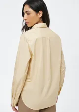 Camisa de corte clásico con cuello camisero, manga larga con puños vueltos y cierre frontal de botones. Presenta un diseño de rayas verticales finas en tono beige.