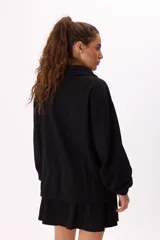 Conjunto deportivo compuesto por un buzo con cierre frontal y una falda corta, confeccionados en algodón liviano. El buzo presenta cuello alto, mangas largas con puños elásticos y un diseño holgado.