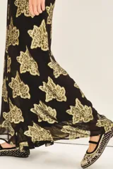 Pantalon de corte amplio y tiro alto, confeccionado en tejido jacquard negro con estampado floral en hilo metalizado dorado. Presenta una silueta fluida y holgada.