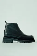 Bota corta de cuero negro, estilo botín chelsea, con puntera cuadrada y suela track gruesa y robusta.