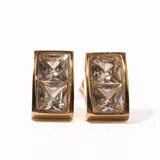 Aros tipo caravana dorados con forma rectangular curva y tres cristales incrustados.