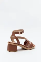 Sandalias negras de cuero sintético con tiras cruzadas y pulsera al tobillo con hebilla metálica. Taco cuadrado bajo.