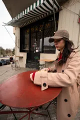 Trench color beige con doble botonadura, cuello clásico, solapas de muesca, cinturón y bolsillos laterales.