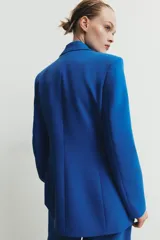 Blazer entallada de cuello solapa y manga larga con hombreras. Presenta bolsillos con solapa en el delantero, forro interior a contraste y cierre frontal con botones forrados.