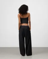 Top negro sin mangas, estilo palabra de honor, con gran volumen frontal fruncido y textura de microcuadros.