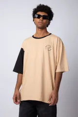 Remera de corte oversize en color beige, con cuello redondo en contraste negro y una manga en color negro. Presenta un pequeño estampado circular en el pecho con la frase 'Don't worry, be happy'.