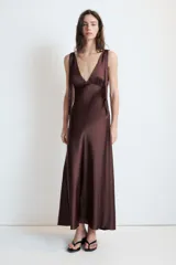 Vestido midi satinado color marrón, con escote en V y tirantes anchos ajustables con lazada en los hombros. Presenta cierre lateral con cremallera oculta.