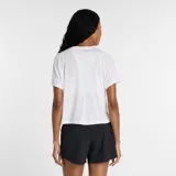 Remera deportiva de mujer New Balance, de corte holgado y largo cropped, con mangas cortas y escote redondo. Presenta aberturas laterales para mayor movilidad y el logo de la marca estampado en el centro del pecho.
