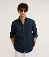 Camisa azul marino de algodón con textura maquinetada, corte comfort, cuello inglés, manga larga y abotonadura frontal.