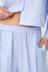 Pijama de algodón a rayas celestes y blancas, compuesto por una camisa de manga larga con botones y un pantalón largo de corte ancho.