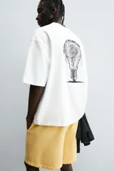 Camiseta de algodón blanca con corte relajado y cuello redondo. Presenta un pequeño bordado en negro con la palabra "BULB" en la parte superior del pecho.