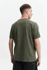 Remera verde militar con estampado de hojas en tono más oscuro, de manga corta, cuello redondo y corte regular.
