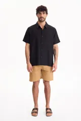 Camisa de manga corta negra, de corte clásico y cuello camisero.