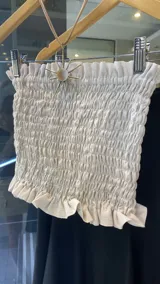 Top color crudo, sin mangas, con frunces en el busto y volados en el ruedo.