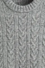 Buzo gris de punto trenzado, confeccionado en una mezcla de lana suave. Presenta cuello redondo y remates acanalados en puños y bajo, con un corte estándar.