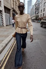 Chaqueta de cuello redondo y manga larga con diseño peplum en el bajo. Confeccionada en tejido efecto ante, cuenta con cierre frontal de cremallera y cinturón fino ajustable en la cintura.