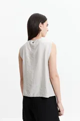 Blusa sin mangas color gris claro con textura rayada vertical y lazo ajustable en el escote.