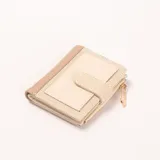 Billetera de mujer en tonos beige y tostado, con cierre de broche y detalle de dije de imperdible dorado en el cierre lateral.