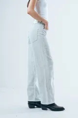Pantalón de jean corte wide leg, color beige con estampado de rayas verticales finas. Presenta tiro alto, cierre frontal con botón y bolsillos laterales.