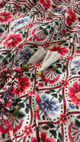 Vestido largo con escote en V, sin mangas y cintura marcada. Presenta un estampado de diseño geométrico y floral con detalles en tonos terracota, crema y azul.