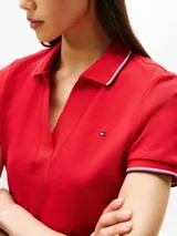 Chomba roja de algodón elástico con corte slim, cuello en V, tapeta abierta y mangas cortas con ribetes blancos y azul marino. Logo de Tommy Hilfiger bordado en el pecho.