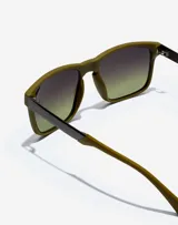 Gafas de sol Hawkers Peak Metal unisex, con montura cuadrada color verde oliva y lentes degradadas de negro a verde.