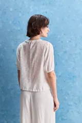 Blusa de manga corta color rosado con estampa orgánica de inspiración floral, cuello redondo y ajuste mediante lazo en el ruedo.