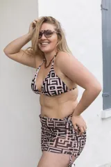 Conjunto de bikini con estampado geométrico en tonos beige y negro, compuesto por un corpiño triangular con tirantes finos y una falda de playa con cordones laterales.