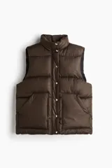 Chaleco acolchado tipo puffer color marrón oscuro, con cuello elevado, cierre frontal oculto por solapa con botones a presión y bolsillos tipo parche en el frente.