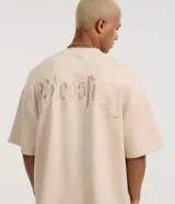 Remera masculina oversize de tejido tipo gamuza sintética (suede) de color negro, con cuello redondo, mangas cortas y detalle de bordado de cruz en el frente.