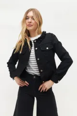 Campera de jean negra con cuello con volados, cierre frontal con botones metálicos y bolsillos con solapa en el pecho.