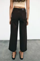 Jeans de tiro alto con diseño wide leg y corte cropped. Presenta cinco bolsillos, cierre frontal con cremallera y botón metálico.