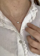 Collar plateado con dije circular con un cristal incrustado.