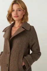 Chaquetón color beige con cuello, abrochadura simple con botón en el cuello, bolsillos ojal y detalle de martingala en mangas. Prenda con forro al tono.