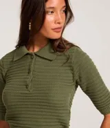 Blusa de punto texturizado color verde militar, con cuello polo, cierre frontal de tres botones y mangas cortas.