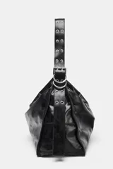Bolso tipo maxi saca de cuero negro, con asa de hombro ajustable adornada con ojales metálicos plateados. Presenta cierre principal de cremallera y bolsillo interior con cierre.