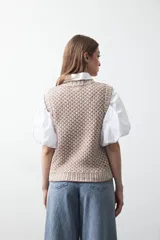 Chaleco tejido de algodón y acrílico, color rojo y blanco con patrón geométrico. Tiene cuello redondo y bordes acanalados en rojo.