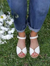 Sandalias planas de cuero color blanco marfil con puntera descubierta y tira ajustable al tobillo, suela tipo yute trenzado.