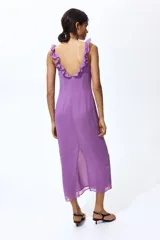 Vestido midi color lila, de corte recto, con escote en V profundo decorado con volados y tiras finas para anudar.