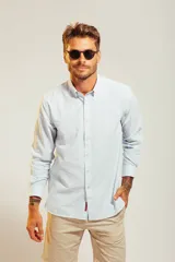 Camisa de vestir blanca de manga larga con cuello abotonado y cierre frontal de botones.