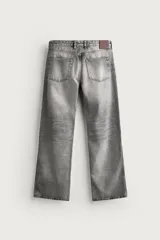 Jeans flare fit de denim de algodón en color gris con efecto lavado. Presentan diseño de cinco bolsillos, tiro medio y cierre frontal con cremallera y botón.