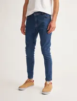 Jean de denim azul oscuro, corte skinny, tiro medio y cinco bolsillos.